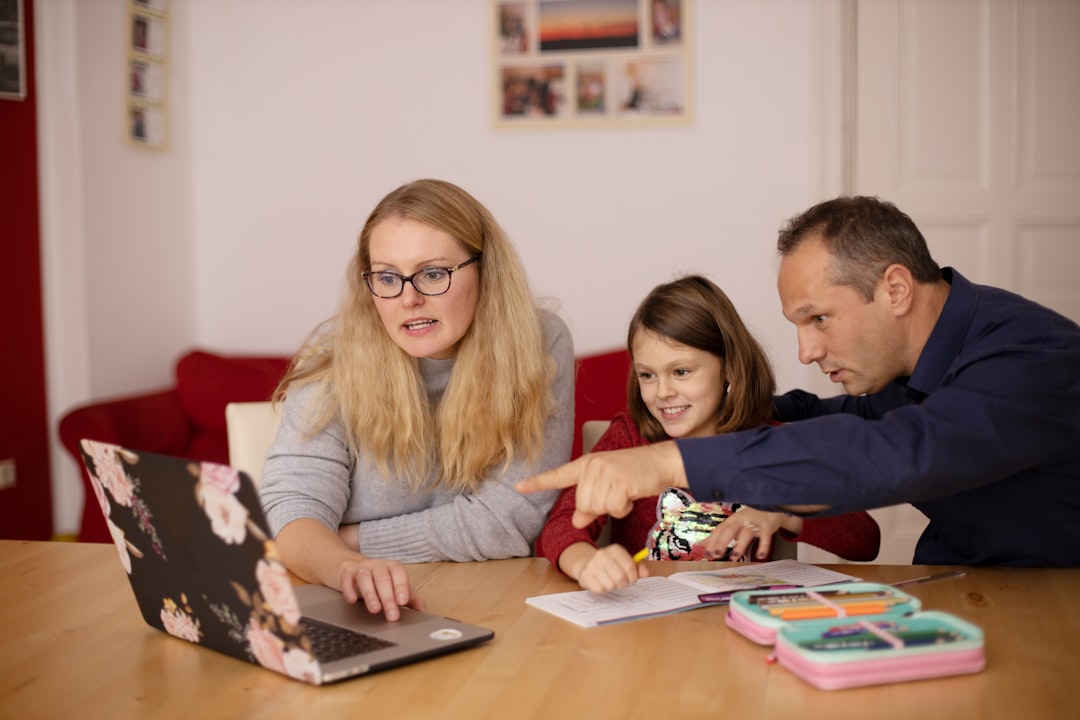 Parents and a child using a laptop together at home, representing family access to technology.