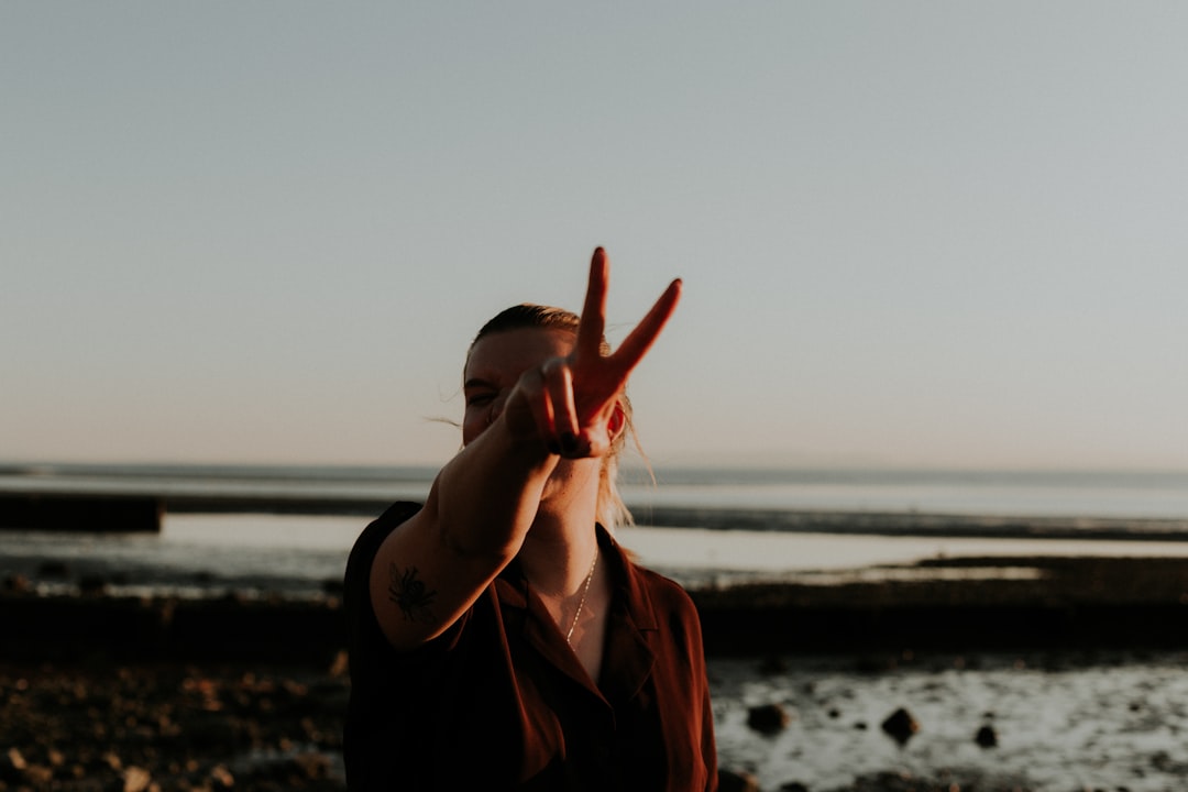Person reflecting by the ocean at sunset, representing mindfulness, emotional release, and peace